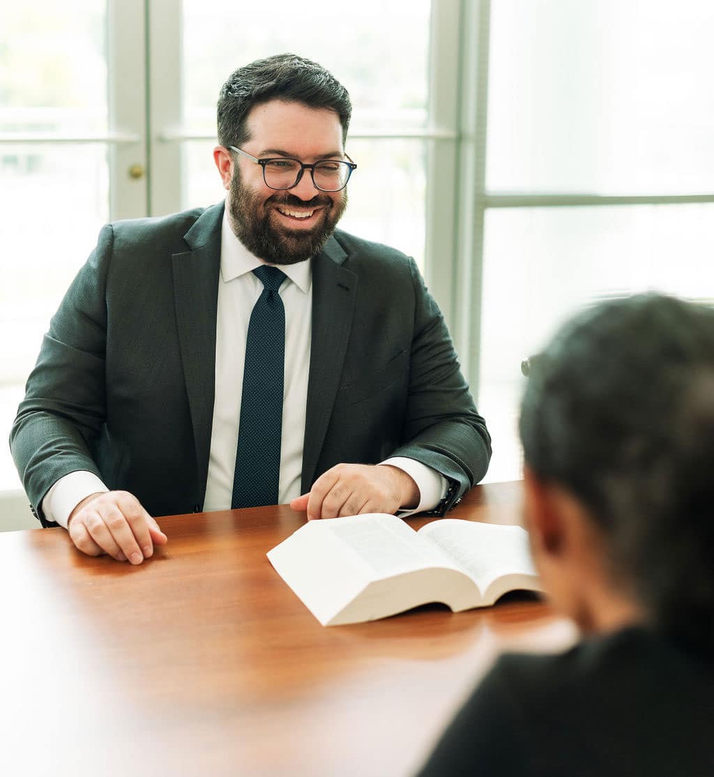 a man in a suit and tie sitting at a table with a book